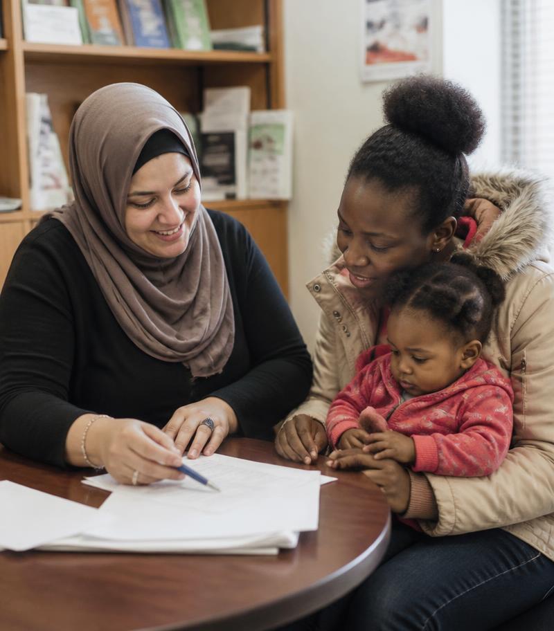 A settlement worker helping a mother complete paperwork